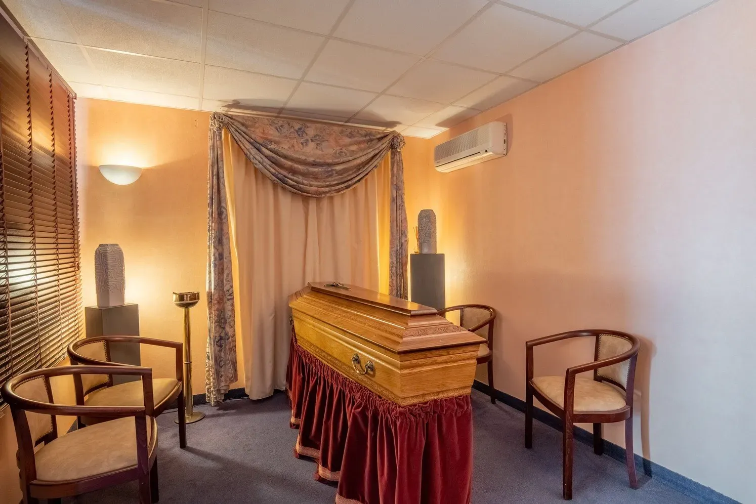 Salon de recueillement avec cercueil en bois et fauteuils pour les familles.